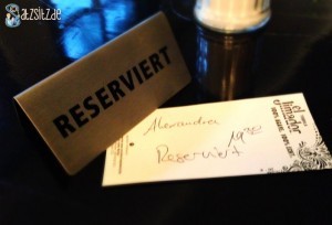 "Reserviert"-Schild auf einem dunklen Tisch. dazu der Zettel: "Alexandra 19:30"