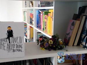 Mark Owen, Robbie Williams und Michael Jackson Bücher neben einem Blumenstrauß im Regal.